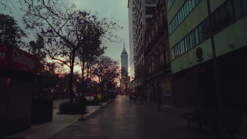 An atmospheric shot reveals the Torre Latinoamericana skyscraper down a quiet Mexico City street at dawn