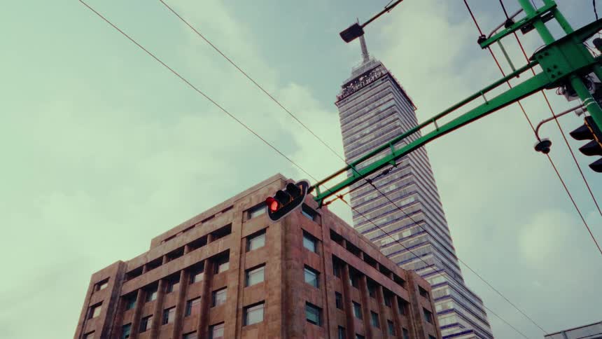 A low-angle view tilts up from a street corner to reveal the iconic Torre Latinoamericana skyscraper in Mexico City