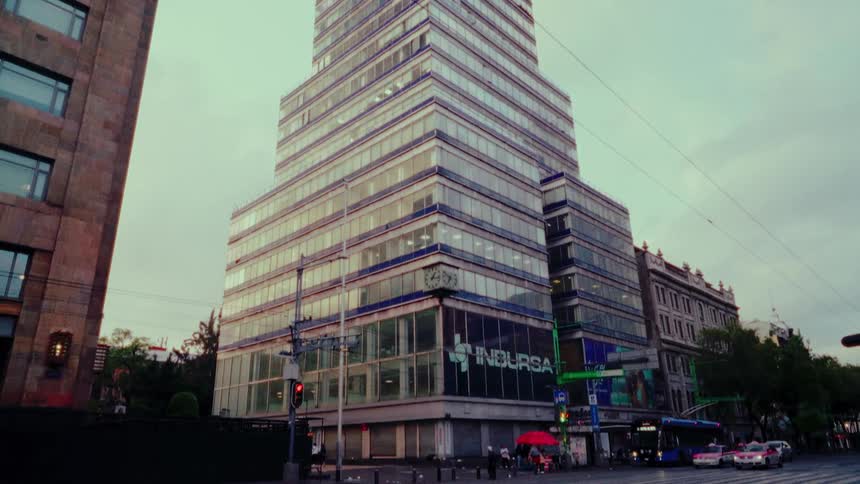 A low-angle view of the iconic Torre Latinoamericana skyscraper in Mexico City, tilting down to reveal the quiet street corner below