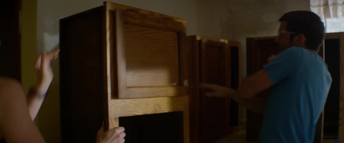 A man and woman rip kitchen cupboards from the wall