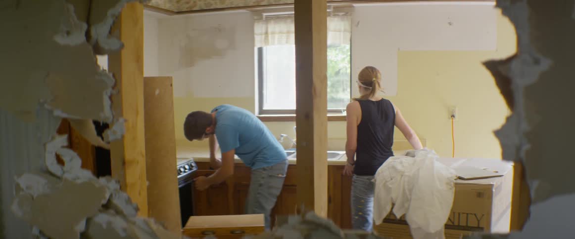 A man and woman look through cabinets in a renovated house