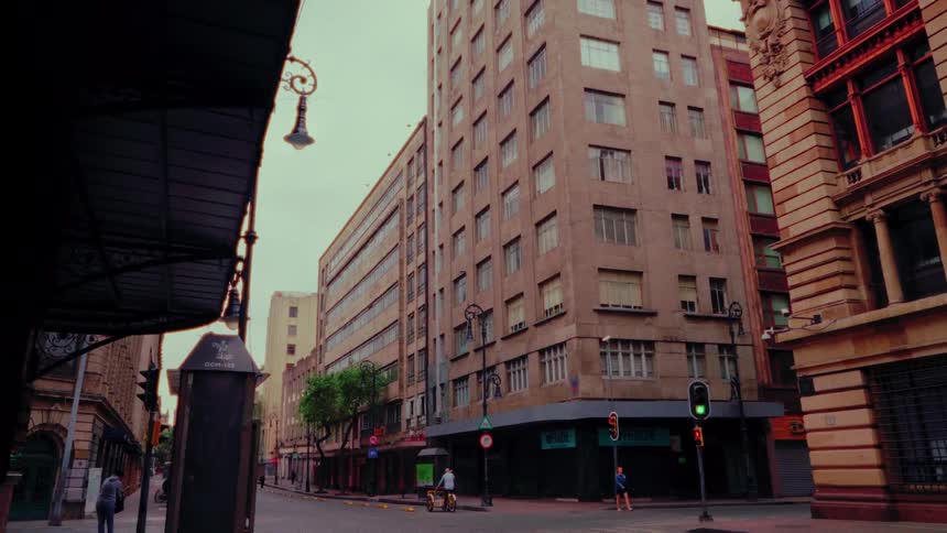 A slow cinematic zoom captures a quiet moment on a city street corner flanked by vintage buildings under an overcast sky