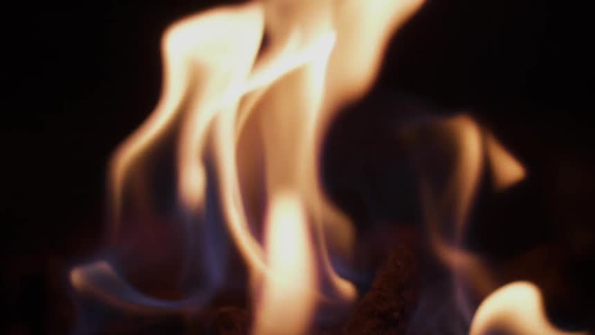 A fire burns giving off a flame in the dark
