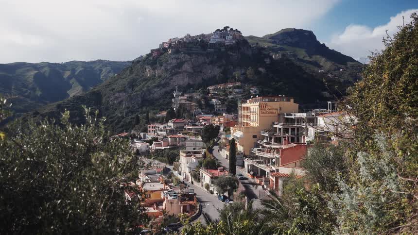 A scenic time-lapse of a historic Italian town built into a lush green mountainside as clouds pass overhead