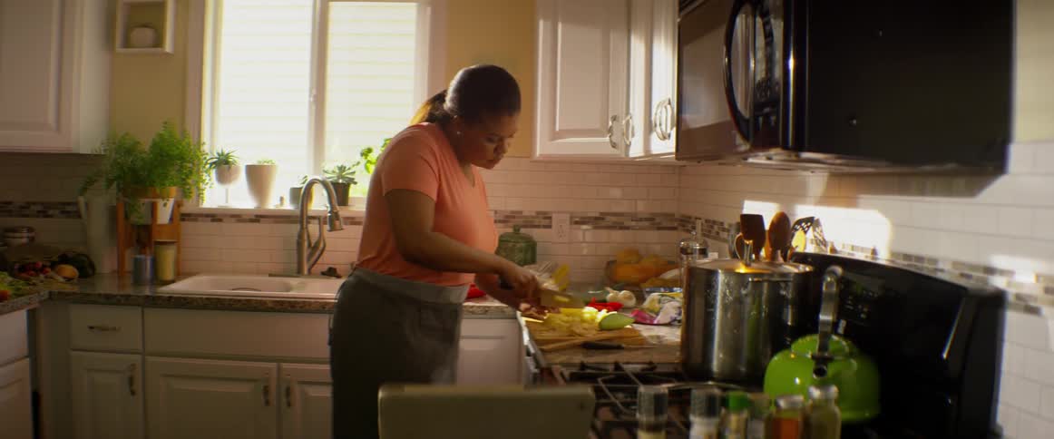 A woman chops vegetables in a kitchen