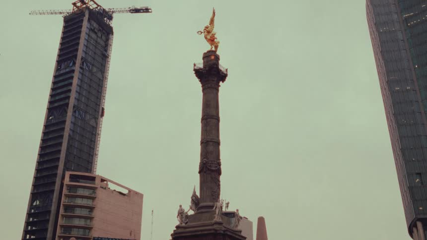 A slow tilt-up reveals the iconic Angel of Independence monument in Mexico City, starting from the crowds gathered at its base