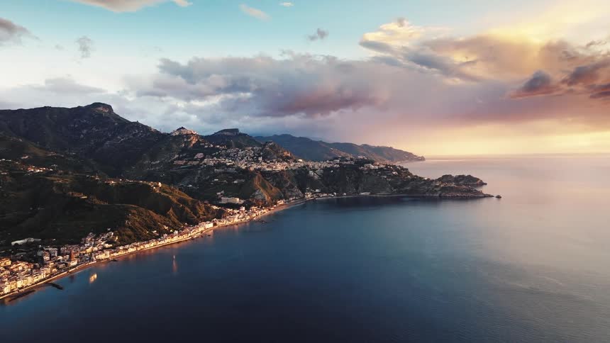 An idyllic coastal town nestled between mountains and the tranquil sea basks in the warm glow of a beautiful sunset
