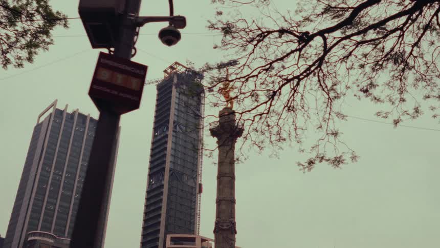 A low-angle cinematic reveal of the Angel of Independence monument set against the modern skyscraper skyline of Mexico City