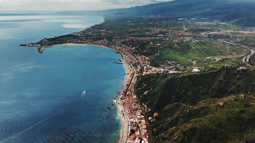 A stunning aerial view of a picturesque coastal city nestled between the vibrant blue ocean and lush green mountains