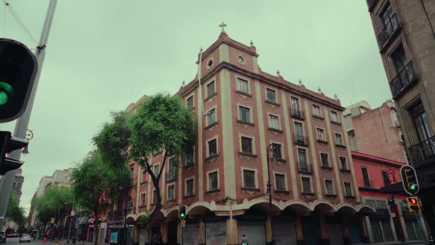 A slow tilt-up shot of a classic architectural building on a quiet city street corner with light traffic