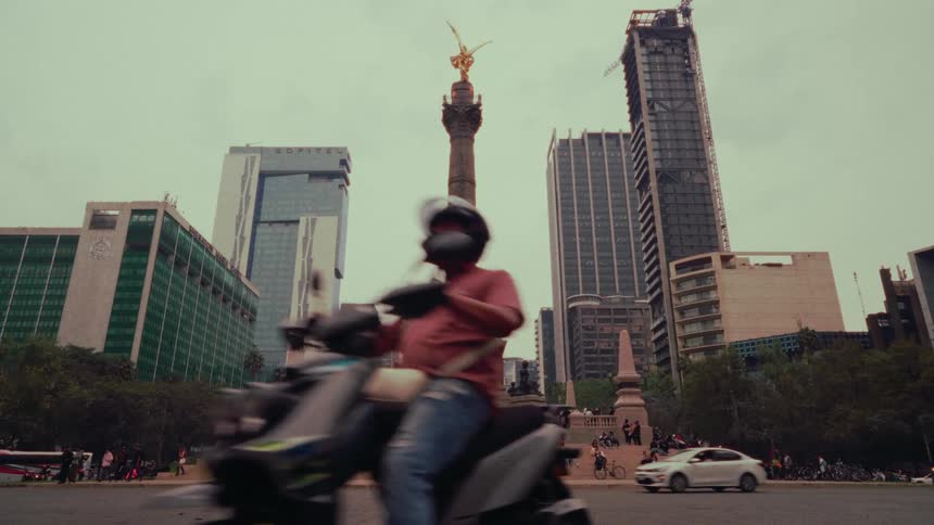 Slow-motion view of traffic and pedestrians around the iconic Angel of Independence monument in the heart of Mexico City on an overcast day