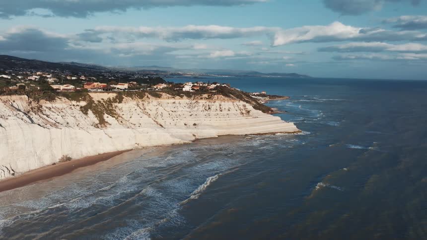A breathtaking aerial view of the iconic white cliffs of Scala dei Turchi in Sicily, Italy, with waves washing ashore