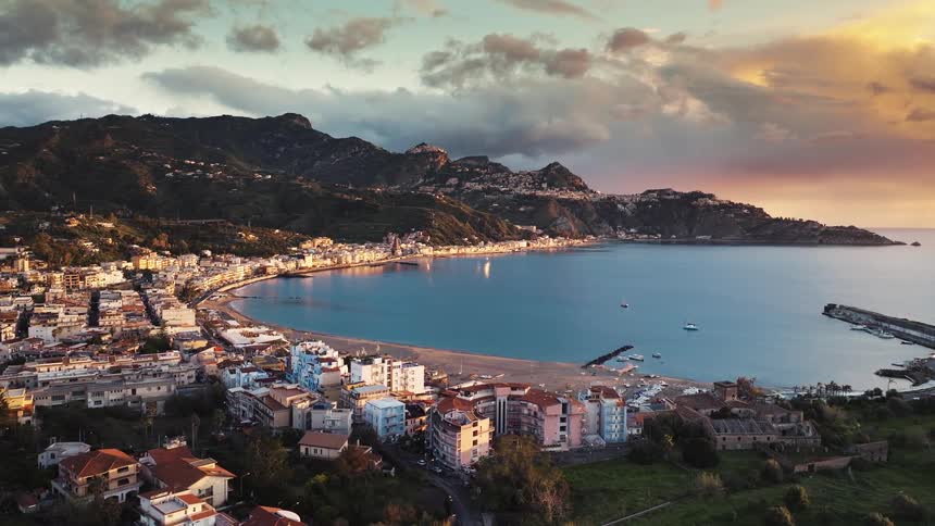 A stunning aerial view captures a picturesque coastal town and its beautiful bay during a colorful and dramatic sunset