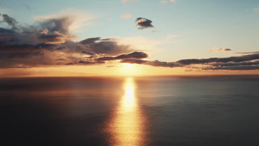 A serene and peaceful cinemagraph captures the golden sunset reflecting beautifully over the calm ocean horizon