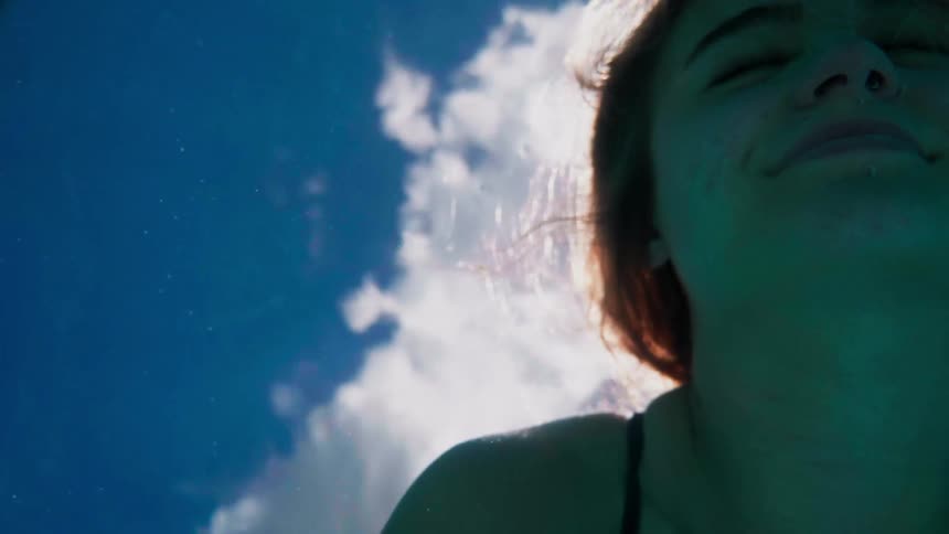 A woman slowly lifts her head out of the water