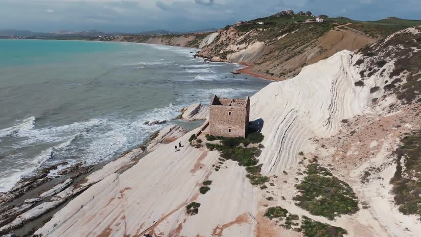A stunning aerial view captures the ruined Torre di Monterosso on the unique white cliffs of Punta Bianca, Sicily