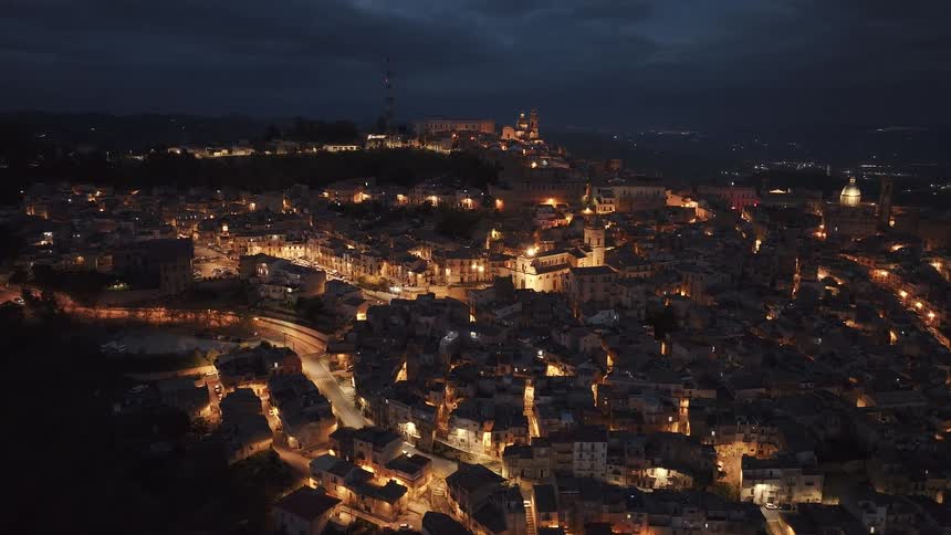 An enchanting aerial view of a sprawling historic city illuminated by warm city lights at night