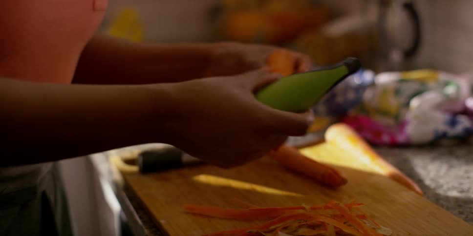 A woman peels carrots in a kitchen