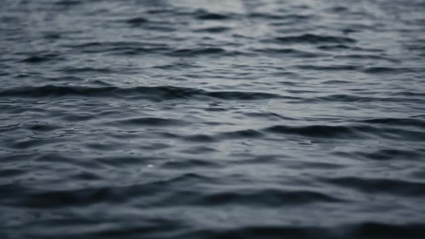 A mesmerizing close-up of dark, moody water with gentle ripples on its surface