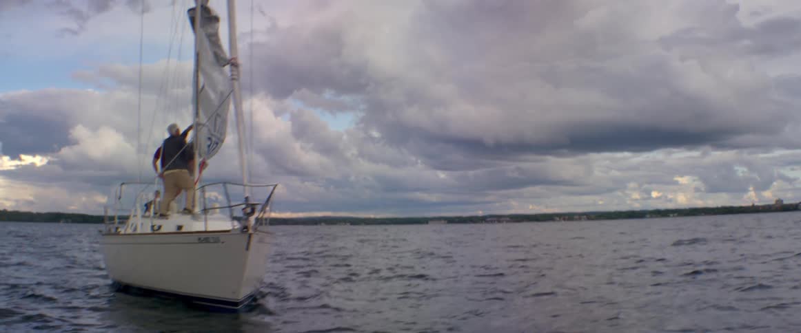 A sailboat floats on a lake on a cloudy day