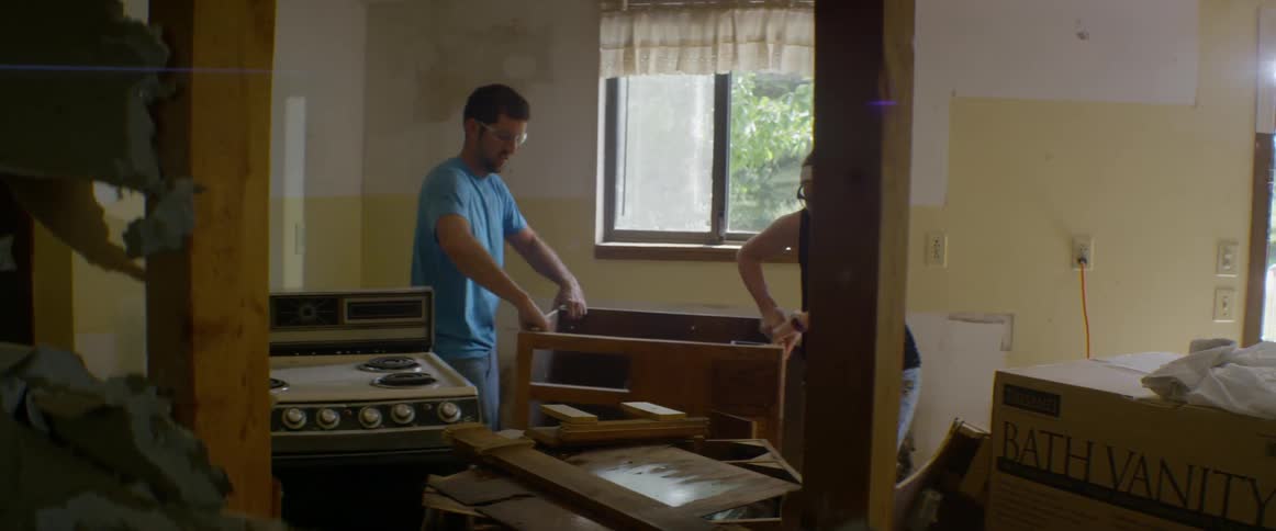A man and woman move cabinets around kitchen