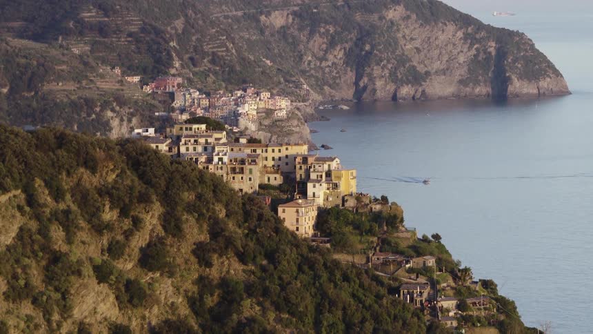 A slow zoom-out reveals the picturesque Italian coastal villages of Corniglia and Manarola in Cinque Terre at golden hour