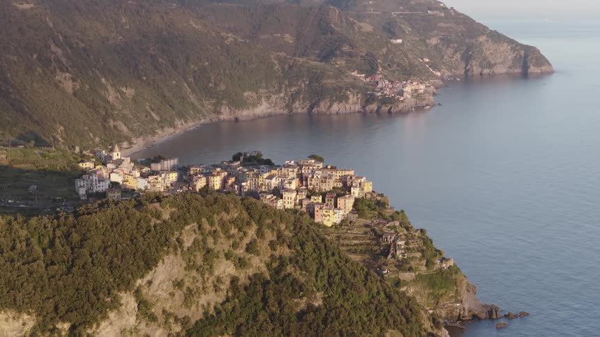 Stunning wide aerial view of the picturesque village of Corniglia in Cinque Terre, Italy, glowing in the warm light of sunset