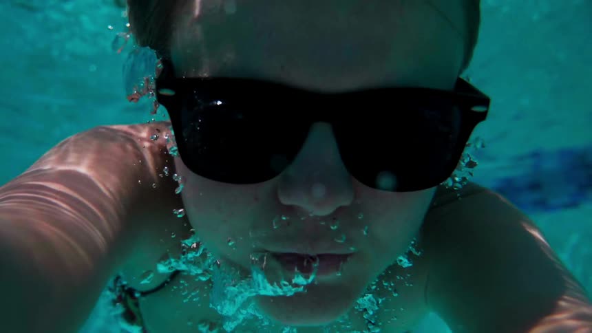 A woman with sunglasses is diving underwater
