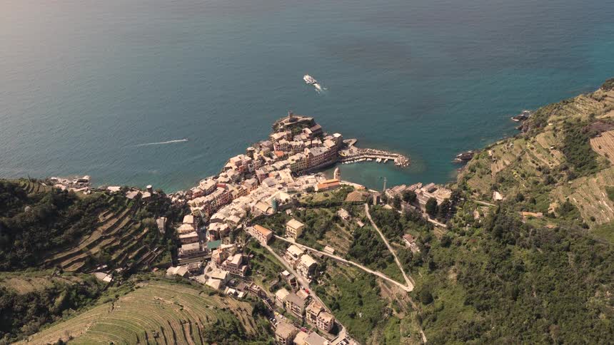 A stunning high-angle view of the picturesque coastal village of Vernazza in Cinque Terre, Italy, nestled on a cliffside overlooking the serene Mediterranean Sea