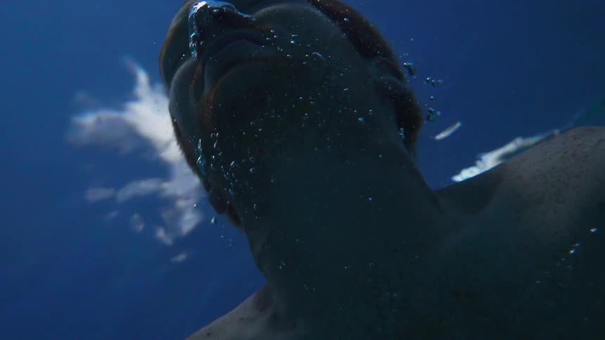 A man slowly hits the surface from underwater