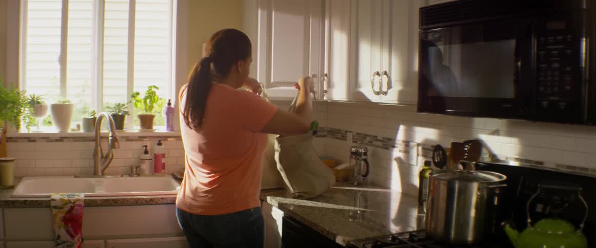 Woman bringing grocery bags into kitchen and setting on counter