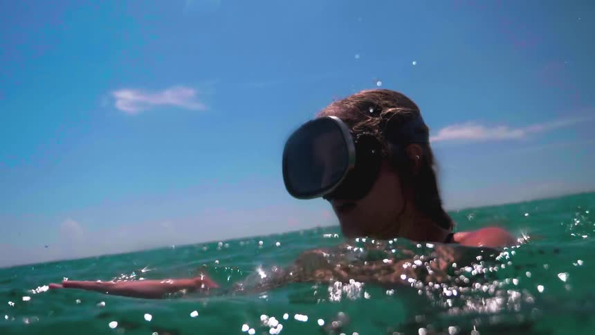 A woman adjusts her goggles in the water