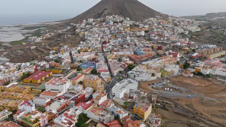A slow aerial drone shot pushes in over the vibrant city of Gáldar, built on the slopes of a volcanic mountain in Gran Canaria