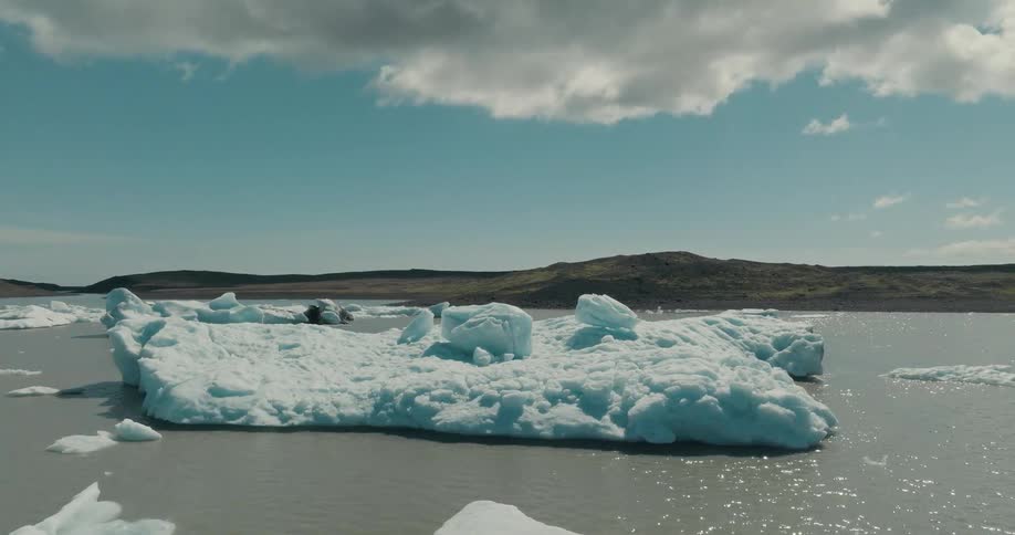 A vast iceberg floats in a tranquil glacier lagoon on a sunny day in the Icelandic wilderness