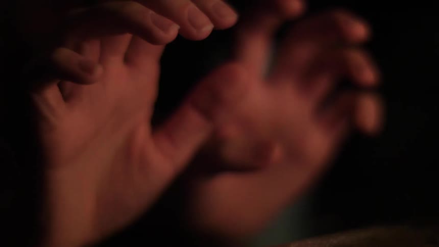 A person moves their fingers over a fire at night