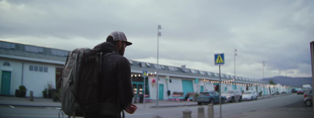 Slow motion shot of a solo traveler with a large backpack walking down a city street on a cloudy day