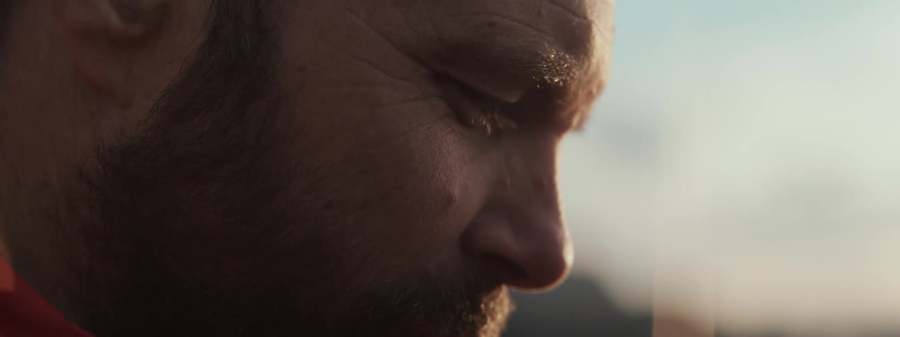 A contemplative man with his eyes closed is shown in a tight profile shot with warm, golden hour light