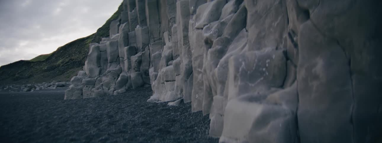 Close-up of Iceland's famous basalt columns on a black sand beach under an overcast sky