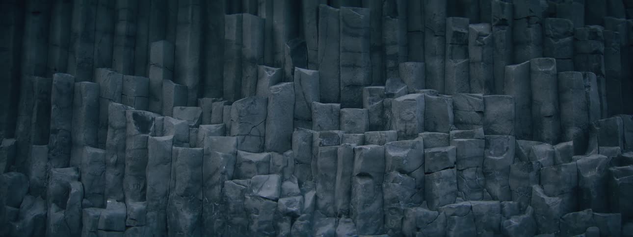 A static close-up shot of unique, dark gray basalt rock column formations