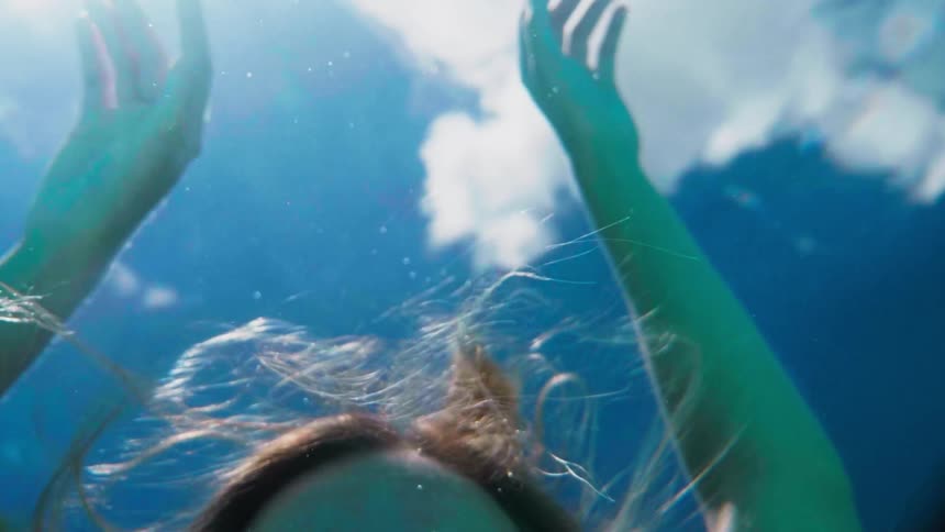 A woman slowly falls under the water