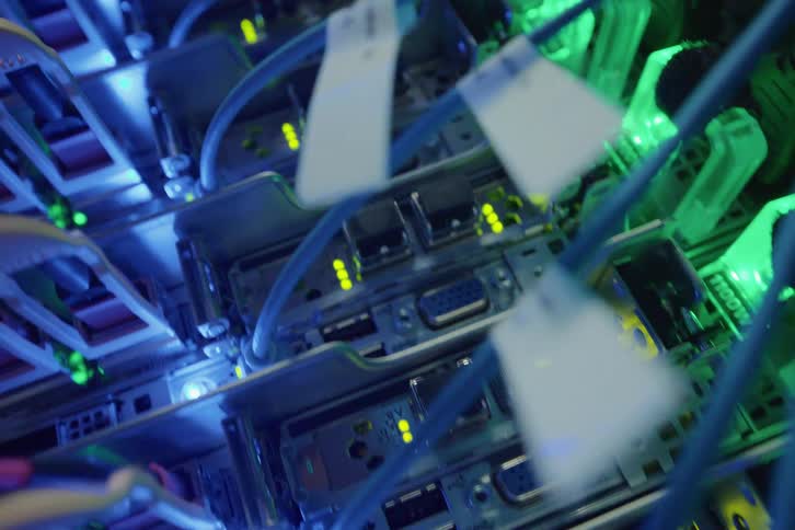 A close-up view of a working data server with flashing LED lights and network cables connected to the back of the server rack