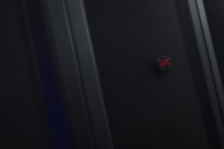 A cinematic slow pan across APC server racks operating in a dimly lit, high-tech data center