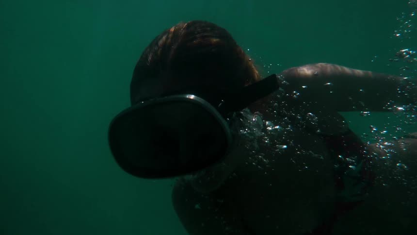 A woman is diving in dark waters