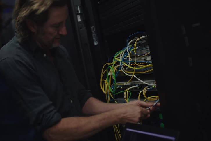 A male IT technician and a female colleague collaborate on server maintenance in a dark data center