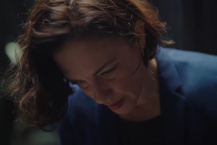 Close-up of a focused businesswoman typing on her laptop in a dark office, who then looks up in surprise