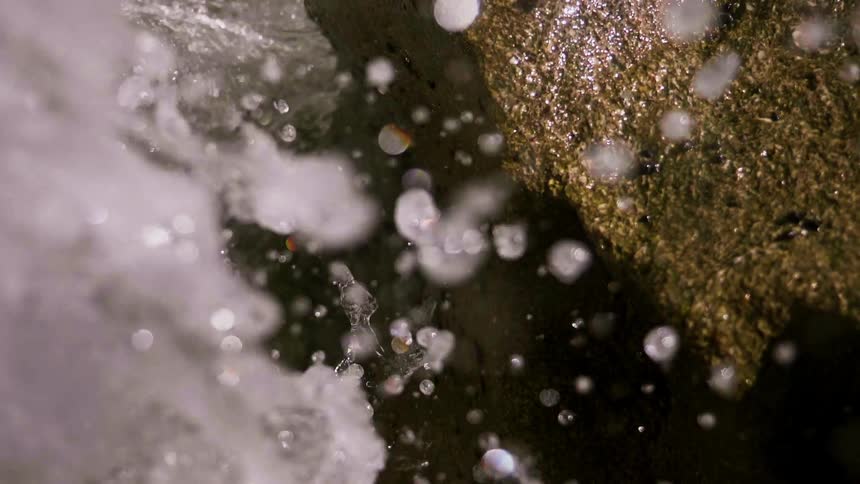 Water splashing up against rock on sunny day