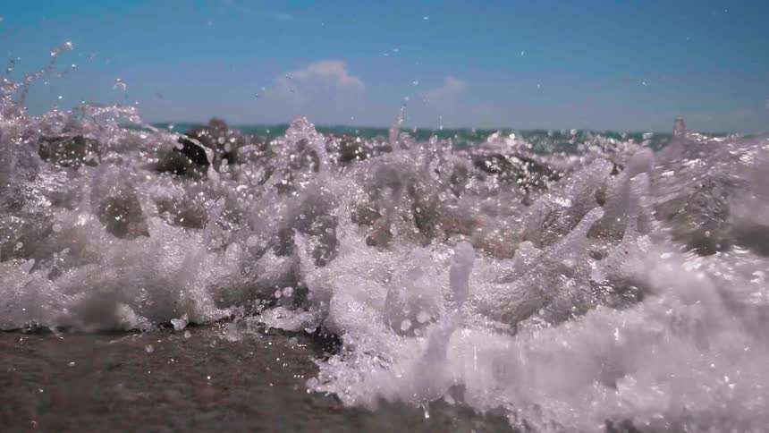 Waves crash against the shore of the sunny beach