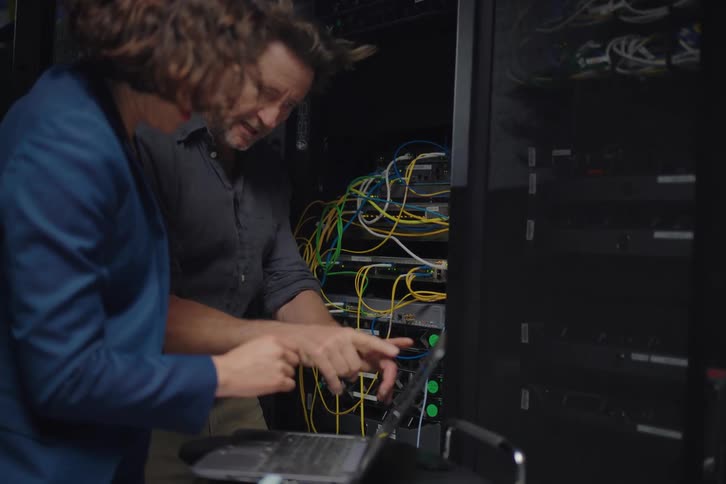 A male and female IT professional collaborate on troubleshooting a network server in a data center