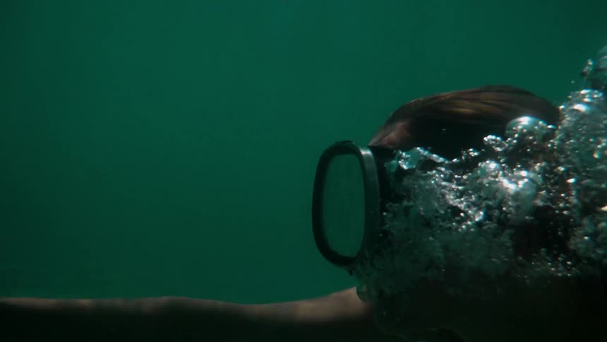 A woman is swimming underwater with goggles
