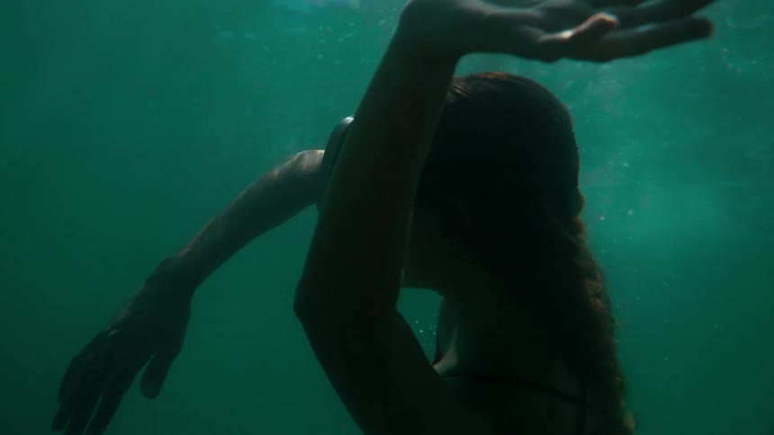 A woman wearing goggles rises to the surface of the water